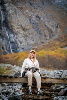 Solitude with nature, girl contemplating a majestic waterfall while sitting on a bridge