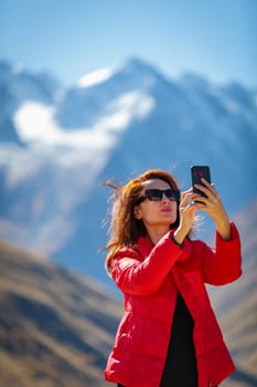 Girl taking selfie, winter mountains in the background.