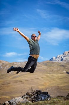 A joyful man on the top of a mountain experiences the flight of the soul and freedom, enveloped in the stunning beauty of the mountainous landscape.