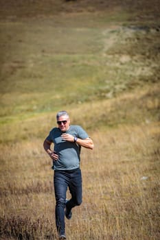 Sporty man actively descends from the mountain, feeling adrenaline and freedom of movement