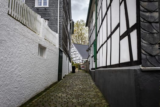 Narrow street with paving stones between white traditional houses in German small town