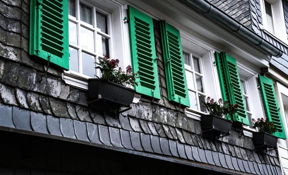 Traditional exterior of germany slate house with open green shutters