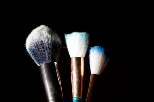 Three makeup brushes on gray background close up