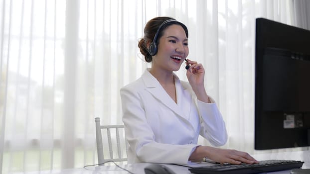 Businesswoman wearing vivancy headset working in office to support remote customer or colleague. Call center, telemarketing, customer support agent provide service on telephone video conference call