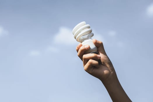 Recyclable electric waste held in hand up on sky background. Hand holding light bulb for recycle reduce and reuse concept to promote clean environment with recycling management. Gyre