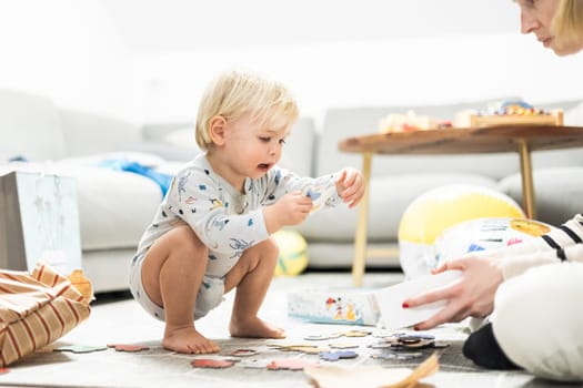 Parents playing games with child. Little toddler doing puzzle. Infant baby boy learns to solve problems and develops cognitive skills. Child development concept.