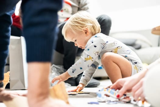 Parents playing games with child. Little toddler doing puzzle. Infant baby boy learns to solve problems and develops cognitive skills. Child development concept.