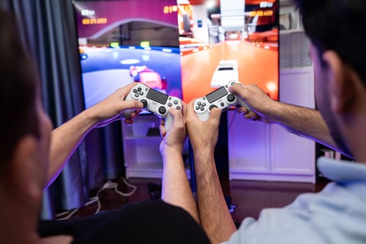 Close up photo of holding joystick crashing or cheerful friends on car racing competition of video game on blurred screen. Concept of lifestyles gamer on weekend with friend in living room. Sellable.