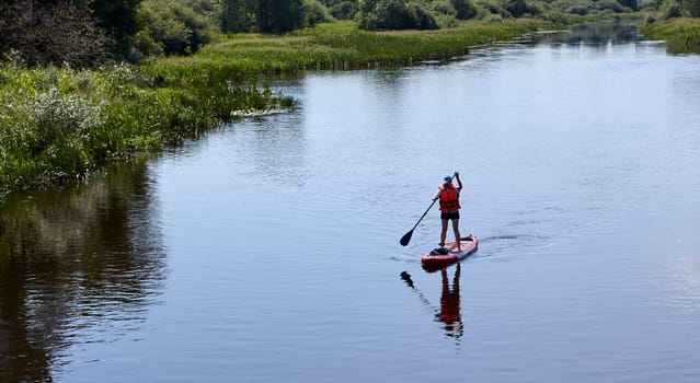 Paddleboarding on lake, aerial view. Stand up paddle boarding (SUP) water sport. Adventure on river on Stand up paddle board. Summer fun, holidays travel on SUP board. Active lifestyle on water.