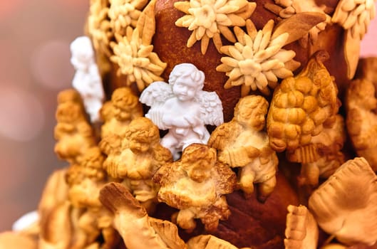 Christmas composition with a figurine of an angel made of sugar on a large pie, surrounded by angels made of dough, close-up. Focus on the foreground.