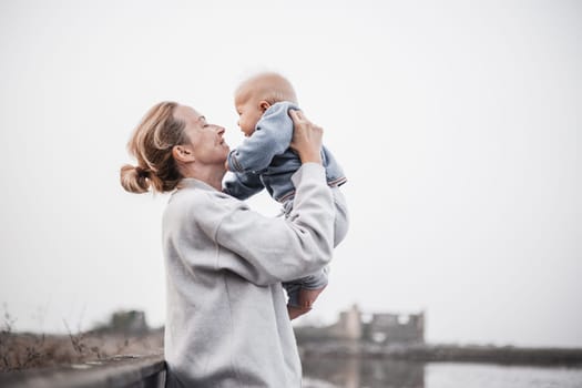 Tender woman caressing her little baby boy infant child outdoors on autumn trip to Secovlje salinas landscape park, Slovenia. Mother's unconditional love for her child