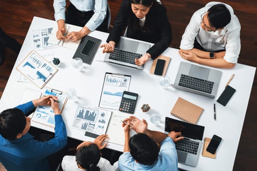 Top view analyst team utilizing BI Fintech to analyze financial data at table in meeting room. Analytic BI dashboard power on paper for business insight and strategic marketing planning. Prudent