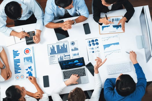 Top view analyst team utilizing BI Fintech to analyze financial data at table in meeting room. Analytic BI dashboard power on paper for business insight and strategic marketing planning. Prudent