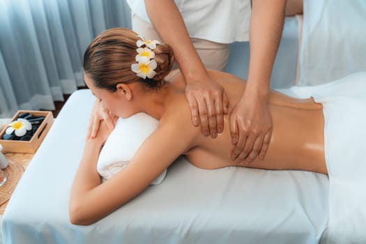 Caucasian woman customer enjoying relaxing anti-stress spa massage and pampering with beauty skin recreation leisure in day light ambient salon spa at luxury resort or hotel. Quiescent