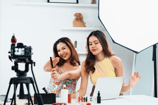 Asian Woman influencer shoot live streaming vlog video review makeup uttermost social media or blog. Happy young girl with cosmetics studio lighting for marketing recording session broadcasting online