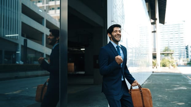 Skilled smart business man dancing with joyful while walking in glass wall. Project manger receive a good news, getting promotion, getting a successful job while express feeling of overjoy. Exultant.