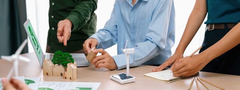 Windmill model represented clean energy and environmental document was placed at green business meeting table while business team discussion about investment. Cropped image. Delineation.