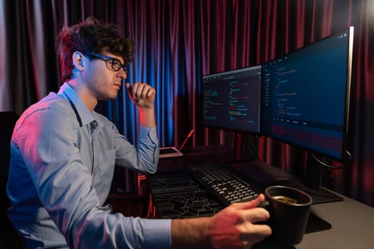 IT developer thinking online software development information coding on pc screen while holding coffee cup at side view, working on design new program for latest version at neon modern office. Gusher.