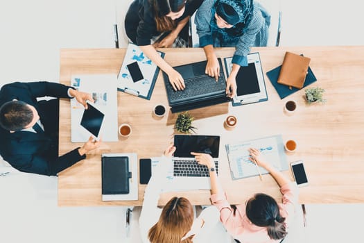 Top view of businessman executive in group meeting with other businessmen and businesswomen in modern office with laptop computer, coffee and document on table. People corporate business team uds