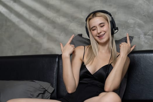 Young woman listening to music on headphone and enjoying meditative isolation on her bed with songs and, promoting a healthy lifestyle and relaxation with musical meditation. Blithe