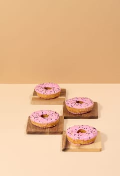 Donut covered with pink glaze and sprinkled with colorful sprinkles, brown background