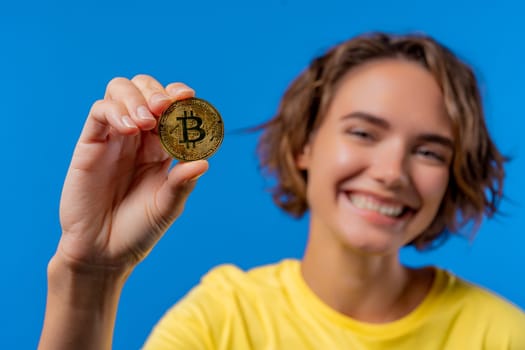 Woman with bitcoin, crypto currency. Golden coin on blue background. Digital exchange, popularity of BTC, symbol of future money, electronics industry, mining concept. High quality photo