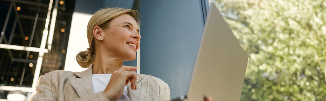 Bottom view of smiling woman manager working laptop on modern building background