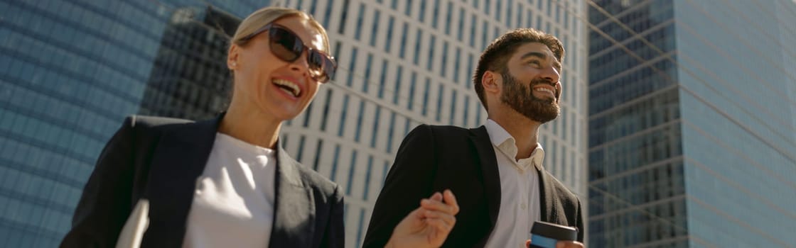 Two colleagues is talking during break time standing on background of modern city skyscrapers