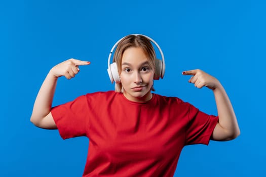 Positive woman listening music, enjoying with headphones on blue studio background. Radio, wireless modern sound technology, online player. High quality 4k