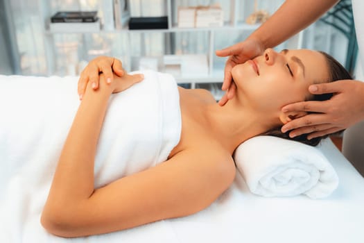 Caucasian woman enjoying relaxing anti-stress head massage and pampering facial beauty skin recreation leisure in dayspa modern light ambient at luxury resort or hotel spa salon. Quiescent