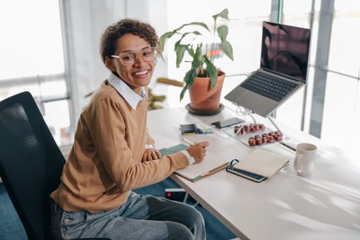 Female freelancer have video conference with client and making notes sitting in cozy coworking