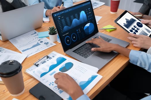 Multiracial analyst team use BI Fintech software to analyze financial data on meeting table. Financial dashboard data display on laptop screen with analyzed chart for marketing indication. Concord