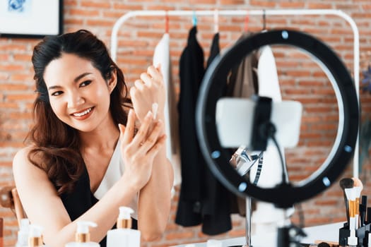 Asian Woman influencer shoot live streaming vlog video review makeup uttermost social media or blog. Happy young girl with cosmetics studio lighting for marketing recording session broadcasting online