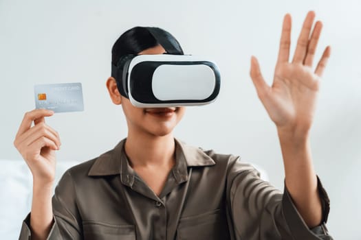 Young woman using virtual reality VR goggle at home for uttermost online shopping experience. The virtual reality VR innovation optimized for digital entertainment lifestyle.