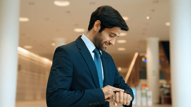 Caucasian smart business man looking at watch while waiting colleague. Executive manager wearing suit while standing at mall with blurred background. Investor wear blue suit check time. Exultant.