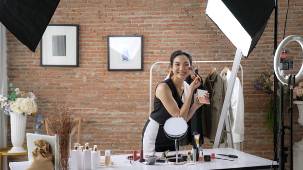 Woman influencer shoot live streaming vlog video review vivancy makeup social media or blog. Happy young girl with cosmetics studio lighting for marketing recording session broadcasting online.