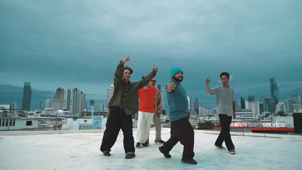 Hispanic hipster dancing surrounded by multicultural friend at city view with blue sky. Group of street dancer performing at rooftop. Active, fun, happy atmosphere. Outdoor sport 2024. Endeavor.