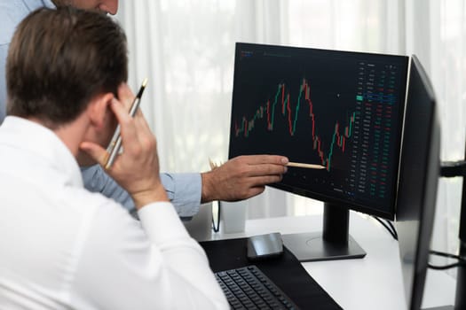 Stock trader pointing highest stock market to present coworker on dynamic valued analysis research on real time monitor screen, cooperating business investment in financial company exchange. Sellable.