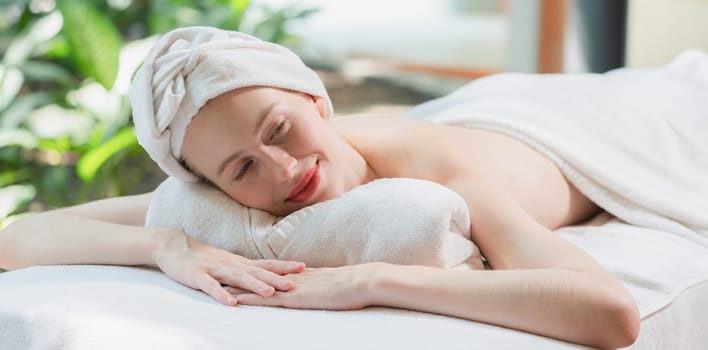 Beautiful young woman relaxes on a spa bed surrounded by nature. ready for a body massage. Attractive female in white towel lying peacefully during waiting for body massage. Close up. Tranquility