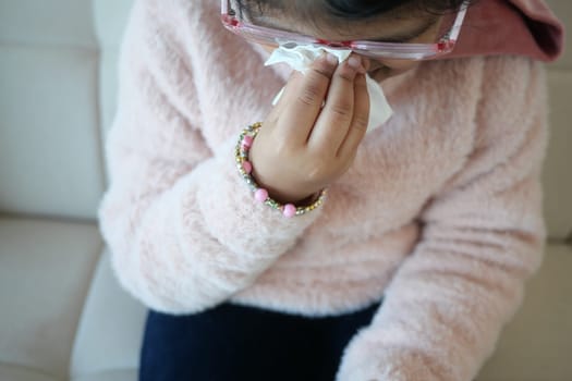 Sick child with flu blow nose with napkin