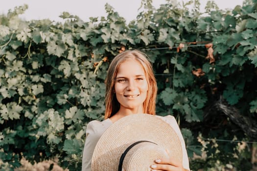 Woman at autumn winery. Portrait of happy woman holding glass of wine and enjoying in vineyard. Elegant young lady in hat toasting with wineglass smiling cheerfully enjoying her stay at vineyard