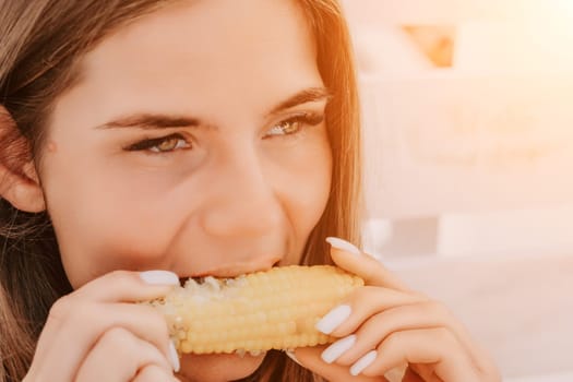 Healthy vegetarian hipster woman in summer outfit eat grilled corn and look to camera. Sexy lady on sea beach sunset or ocean sunrise. Travel, explore, active yoga and meditation lifestyle concept.