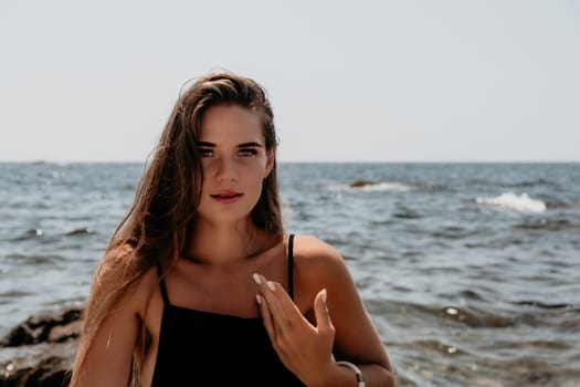 Woman travel sea. Young Happy woman in a long red dress posing on a beach near the sea on background of volcanic rocks, like in Iceland, sharing travel adventure journey