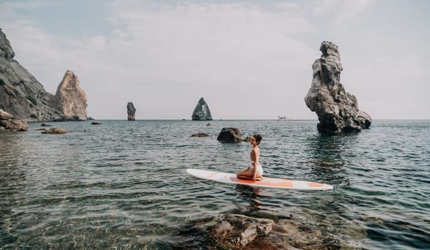 Woman sup yoga. Middle age sporty woman practising yoga pilates on paddle sup surfboard. Female stretching doing workout on sea water. Modern individual hipster outdoor summer sport activity