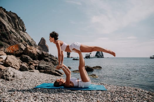 Woman sea yoga. Back view of free calm happy satisfied woman with long hair standing on top rock with yoga position against of sky by the sea. Healthy lifestyle outdoors in nature, fitness concept.