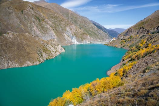 A breathtaking, tranquil blue reservoir nestled amidst a serene mountain landscape with lush, vibrant vegetation. The stunning natural beauty is a perfect depiction of peacefulness and serenity.