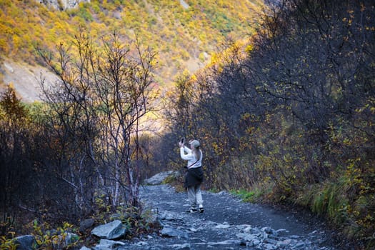 Young woman taking pictures of beautiful mountains with camera, majesty of nature and photography