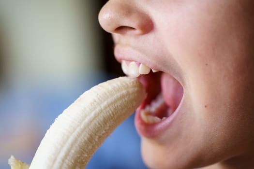 Crop unrecognizable teenage girl with mouth open about to eat fresh peeled banana at home