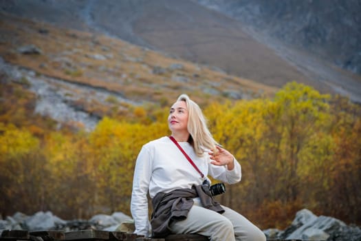 Domination of nature, girl sitting on the bridge, contemplating the power of the waterfall in the mountains