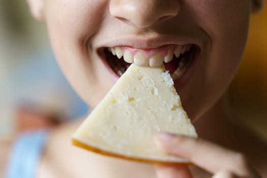 Closeup of anonymous teenage girl eating fresh cheese slice at home